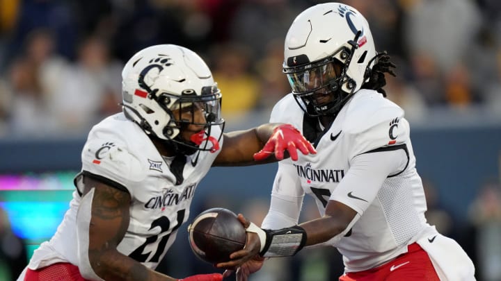 Cincinnati Bearcats quarterback Emory Jones (5) hands the ball of to Cincinnati Bearcats running back Corey Kiner (21) in the third quarter during an NCAA college football game between the Cincinnati Bearcats and the West Virginia Mountaineers, Saturday, Nov. 18, 2023, at Milan Puskar Stadium in Morgantown, W. Va. The West Virginia Mountaineers won, 42-21.