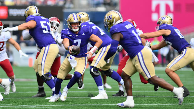 Huskies quarterback Will Rogers (7) hands the ball off to Jonah Coleman (1) during the first half of the Apple Cup.