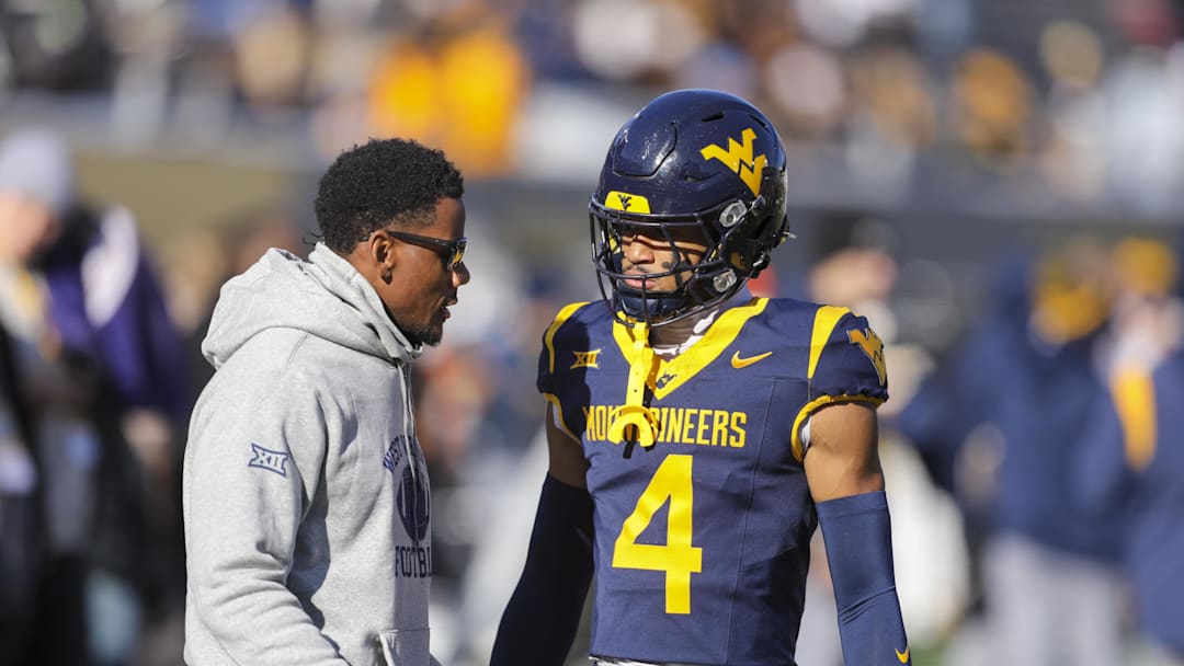 Nov 29, 2025; Morgantown, West Virginia, USA; West Virginia Mountaineers wide receiver Cam Vaughn (4) talks to West Virginia Mountaineers assistant coach Pat White during warmups prior to their game against the Texas Tech Red Raiders at Milan Puskar Stadium. Mandatory Credit: Ben Queen-Imagn Images
