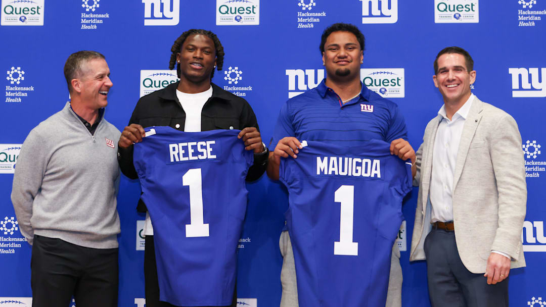 Apr 24, 2026; East Rutherford, NJ, USA; New York Giants draft picks Arvell Reese and Francis Mauigoa, Head Coach John Harbaugh (left) and General Manager Joe Schoen  (right) pose for a photo during the introductory press conference at Quest Diagnostics Training Center.