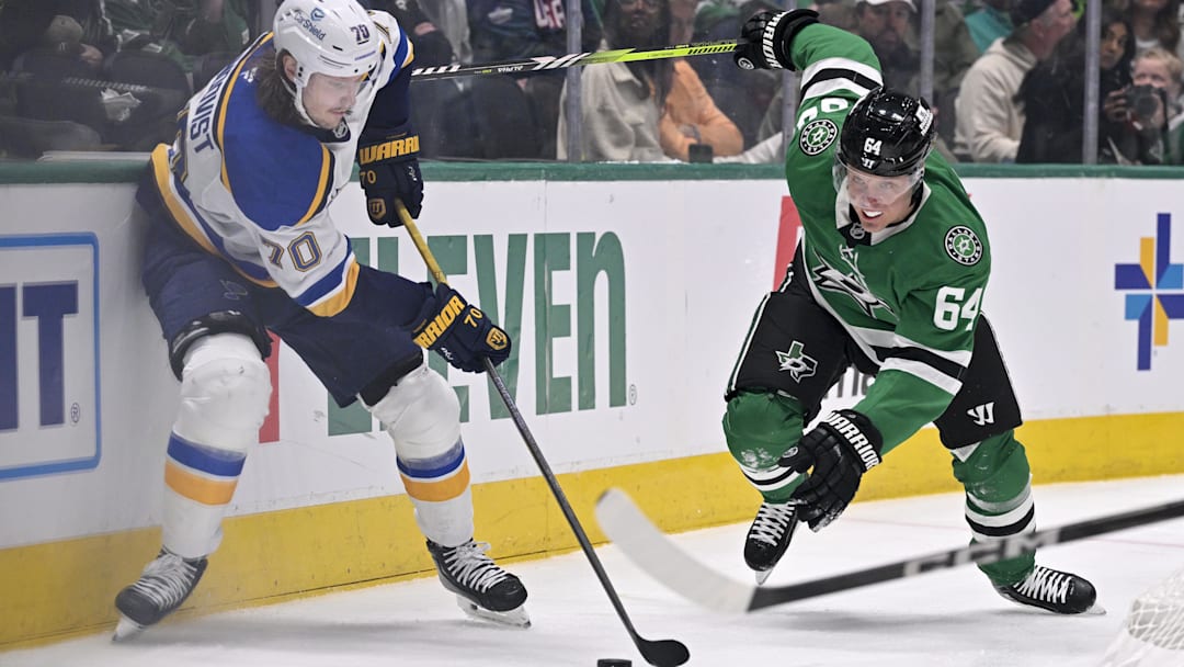 Mar 2, 2025; Dallas, Texas, USA; St. Louis Blues center Oskar Sundqvist (70) and Dallas Stars center Mikael Granlund (64) battle for control of the puck during the first period at the American Airlines Center. Mandatory Credit: Jerome Miron-Imagn Images