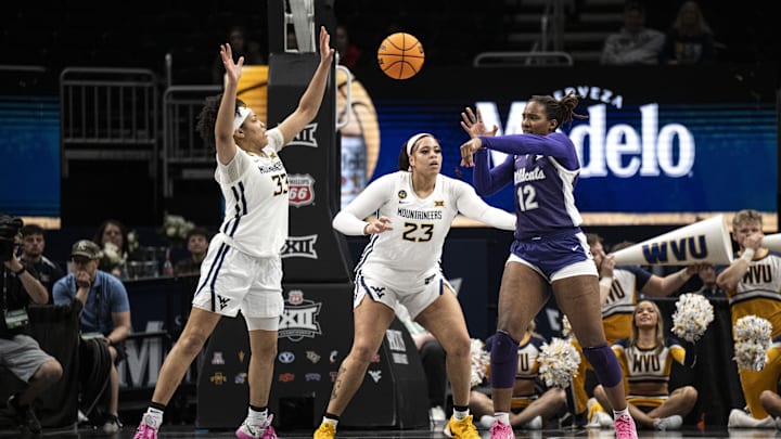 Mar 7, 2025; Kansas City, MO, USA; Kansas State Wildcats forward Kennedy Taylor (12) passes the ball while defended by West Virginia Mountaineers forward Tirzah Moore (33) and forward Jordan Thomas (23) in the second quarter at T-Mobile Center. Mandatory Credit: Amy Kontras-Imagn Images
