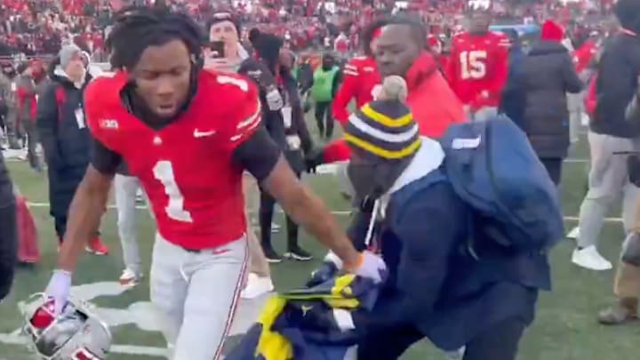 Ohio State football defensive back Davison Igbinosun (#1) and Michigan alum Jason Avant jostle for control of the Wolverines flag during an on-field brawl between the two teams following the game at Ohio Stadium on November 30, 2024. 