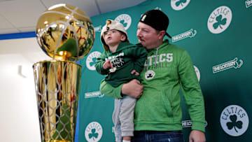 Kevin Briand holds his son Landon Briand, 2, to take a look at the Celtics 2024 NBA Champion trophy during its stop at the Mass Lottery office at the Industrial Park in New Bedford where fans got a chance to take photos with it.