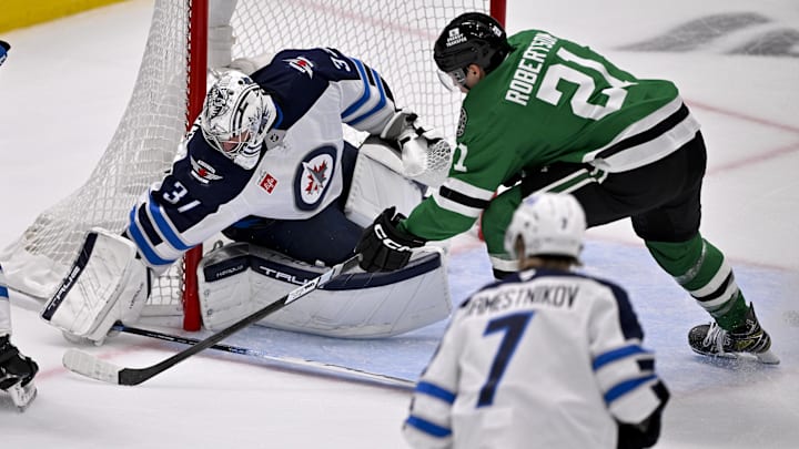 May 17, 2025; Dallas, Texas, USA; Winnipeg Jets goaltender Connor Hellebuyck (37) stops a shot by Dallas Stars left wing Jason Robertson (21) during the first period in game six of the second round of the 2025 Stanley Cup Playoffs at American Airlines Center. Mandatory Credit: Jerome Miron-Imagn Images