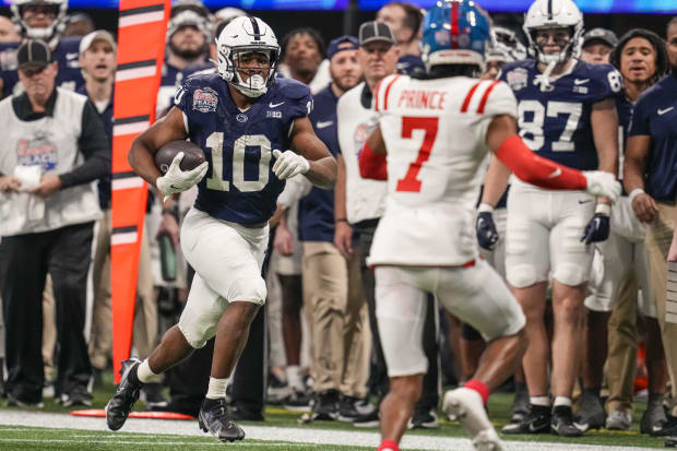 Penn State's Nicholas Singleton runs with the football as a player runs toward him.