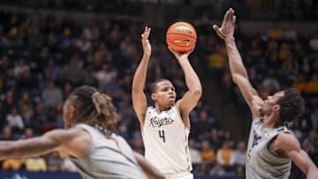 Mar 8, 2025; Morgantown, West Virginia, USA; UCF Knights guard Keyshawn Hall (4) shoots a three pointer over West Virginia Mountaineers guard Toby Okani (5) during the second half at WVU Coliseum. Mandatory Credit: Ben Queen-Imagn Images