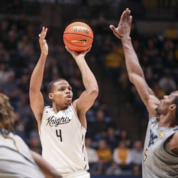 Mar 8, 2025; Morgantown, West Virginia, USA; UCF Knights guard Keyshawn Hall (4) shoots a three pointer over West Virginia Mountaineers guard Toby Okani (5) during the second half at WVU Coliseum. Mandatory Credit: Ben Queen-Imagn Images