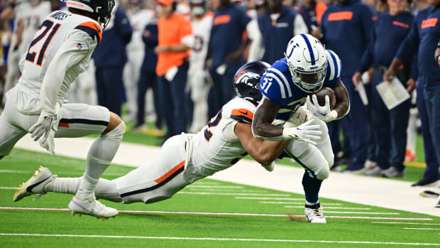 Colts running back Tyler Goodson (blue jersey; white pants/helmet) runs through a tackler for extra yardage. 