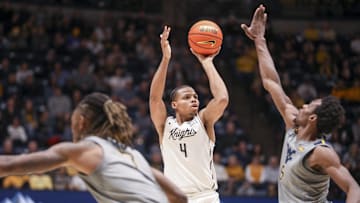 Mar 8, 2025; Morgantown, West Virginia, USA; UCF Knights guard Keyshawn Hall (4) shoots a three pointer over West Virginia Mountaineers guard Toby Okani (5) during the second half at WVU Coliseum. Mandatory Credit: Ben Queen-Imagn Images