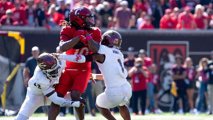 Arizona State Sun Devils defensive back Xavion Alford (2) and Arizona State Sun Devils defensive back Keith Abney II (1) tackle Cincinnati Bearcats wide receiver Jamoi Mayes (10) in the first quarter of the College Football game at Nippert Stadium in Cincinnati on Saturday, Oct. 19, 2024.