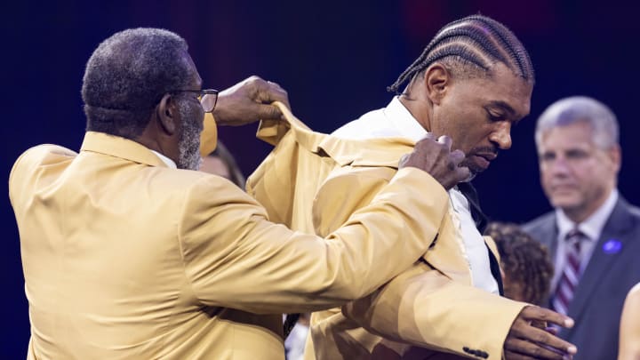 Aug 2, 2024; Canton, OH, USA; Julius Peppers, right, receives his gold jacket from Joe Greene at the 2024 Pro Football Hall of Fame Enshrines gold jacket dinner at Canton Memorial Civic Center. Mandatory Credit: Scott Galvin-USA TODAY Sports