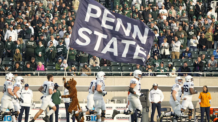 The Penn State Nittany Lion mascot runs with a Penn State flag