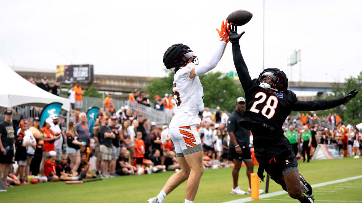 Cincinnati Bengals wide receiver Charlie Jones (15) goes up for a catch as Cincinnati Bengals cornerback Josh Newton (28) defends at Cincinnati Bengals training camp on the Kettering Health Practice Fields in Cincinnati on Sunday, July 28, 2024.