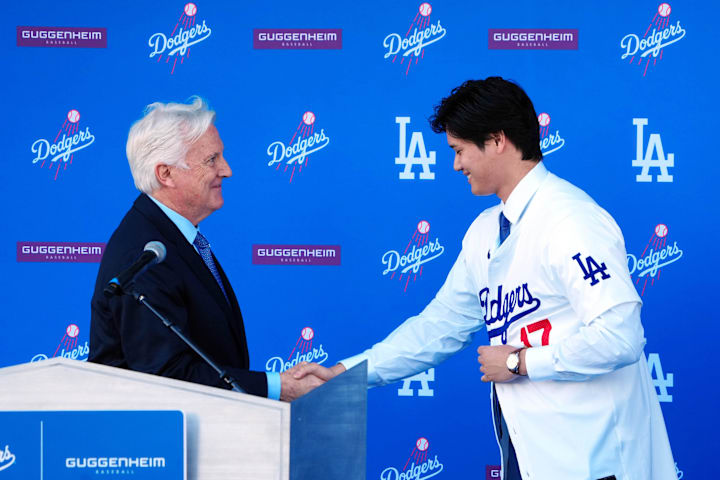 Los Angeles Dodgers player Shohei Ohtani shakes hands with Dodgers owner Mark Walter at an introductory press conference.