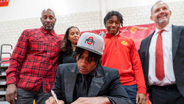 Quincy Porter signs a commitment letter to play football for The Ohio State University while his family and coach stand behind him during a Commitment Day Ceremony for 8 Bergen Catholic athletes at Bergen Catholic High School in Oradell on Wednesday, Dec. 4, 2024.
