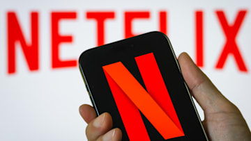 Hand Holding Smartphone Displaying Netflix (NFLX) Logo with Background Branding