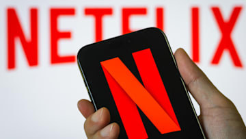 Hand Holding Smartphone Displaying Netflix (NFLX) Logo with Background Branding