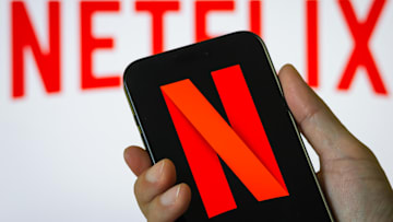 Hand Holding Smartphone Displaying Netflix (NFLX) Logo with Background Branding