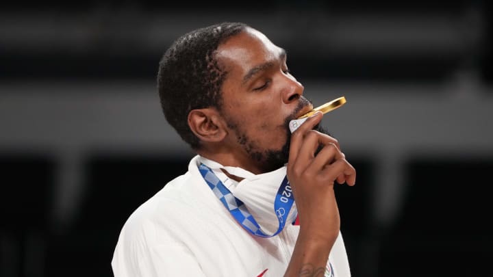 United States forward Kevin Durant bits his gold medal during the Tokyo 2020 Olympic Summer Games. United States forward Kevin Durant bits his gold medal during the Tokyo 2020 Olympic Summer Games.