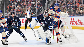 Dec 6, 2025; Edmonton, Alberta, CAN; Edmonton Oilers center Connor McDavid (97) and Winnipeg Jets goalie Eric Comrie (1) collide during the first period at Rogers Place. Mandatory Credit: Walter Tychnowicz-Imagn Images