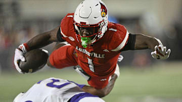 Sep 5, 2025; Louisville, Kentucky, USA;  Louisville Cardinals running back Isaac Brown (1) is upended by James Madison Dukes cornerback Elijah Culp (2) during the first half at L&N Federal Credit Union Stadium. Mandatory Credit: Jamie Rhodes-Imagn Images