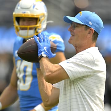 Sep 8, 2024; Inglewood, California, USA; Los Angeles Chargers head coach Jim Harbaugh catches the ball for quarterback Justin Herbert (10) as he warms up prior to the game against the Los Angeles Chargers at SoFi Stadium. Mandatory Credit: Jayne Kamin-Oncea-Imagn Images