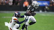 Dec 7, 2025; Paradise, Nevada, USA;  Las Vegas Raiders running back Ashton Jeanty (2) carries the ball as Denver Broncos cornerback Jahdae Barron (23) defends during the first half at Allegiant Stadium. Mandatory Credit: Kirby Lee-Imagn Images