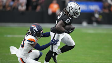 Dec 7, 2025; Paradise, Nevada, USA;  Las Vegas Raiders running back Ashton Jeanty (2) carries the ball as Denver Broncos cornerback Jahdae Barron (23) defends during the first half at Allegiant Stadium. Mandatory Credit: Kirby Lee-Imagn Images