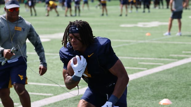 West Virginia University running back Jahiem White running through a ball security drill with offensive coordinator Chad Scot