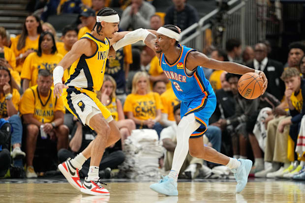Oklahoma City Thunder guard Shai Gilgeous-Alexander dribbles the ball defended by Indiana Pacers guard Andrew Nembhard.