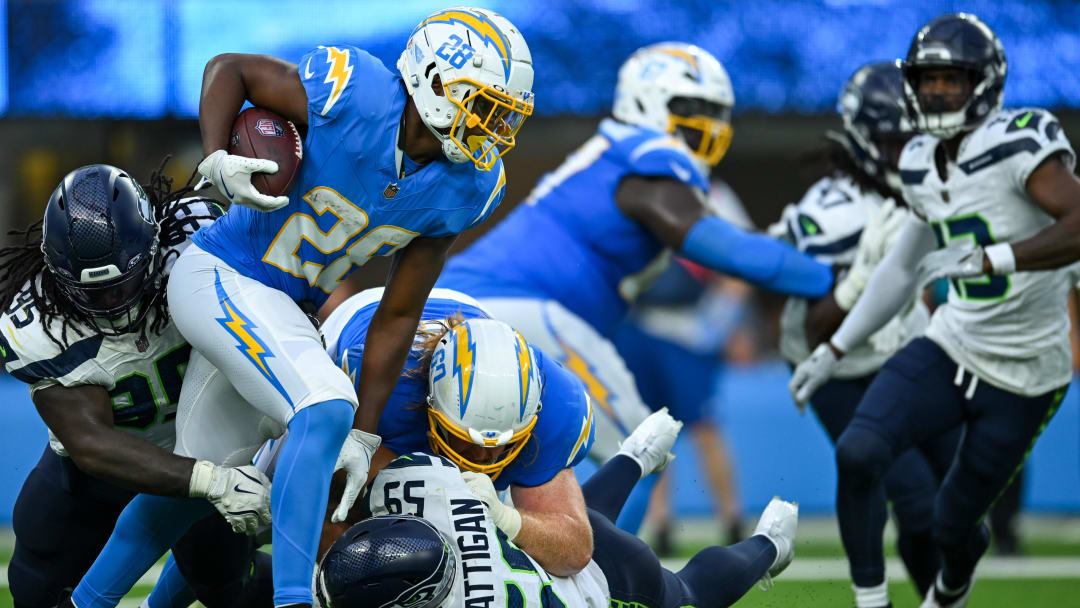 Aug 10, 2024; Inglewood, California, USA; Los Angeles Chargers running back Isaiah Spiller (28) carries the ball against Seattle Seahawks linebacker Jon Rhattigan (59) and defensive end Myles Adams (95) during the third quarter at SoFi Stadium. Mandatory Credit: Jonathan Hui-USA TODAY Sports