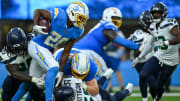 Aug 10, 2024; Inglewood, California, USA; Los Angeles Chargers running back Isaiah Spiller (28) carries the ball against Seattle Seahawks linebacker Jon Rhattigan (59) and defensive end Myles Adams (95) during the third quarter at SoFi Stadium. Mandatory Credit: Jonathan Hui-USA TODAY Sports