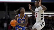 Feb 2, 2025; Cincinnati, Ohio, USA;  West Virginia Mountaineers guard Javon Small (7) controls the ball against Cincinnati Bearcats guard Jizzle James (2) in the second half at Fifth Third Arena. Mandatory Credit: Aaron Doster-Imagn Images