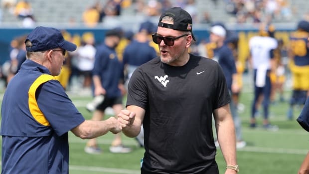 Former West Virginia University specialist Pat McAfee greets equipment manager Dan Nehlen prior to the Gold-Blue Spring Game.