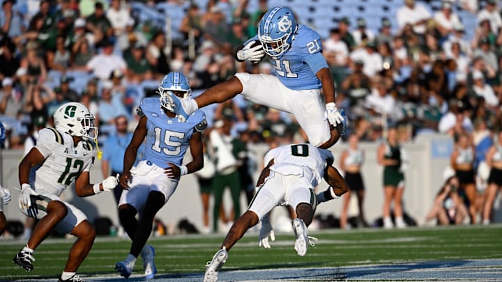 Sep 7, 2024; Chapel Hill, North Carolina, USA; North Carolina Tar Heels running back Davion Gause (21) jumps over Charlotte 49ers defensive back Al-Ma'hi Ali (0) in the fourth quarter at Kenan Memorial Stadium. Mandatory Credit: Bob Donnan-Imagn Images