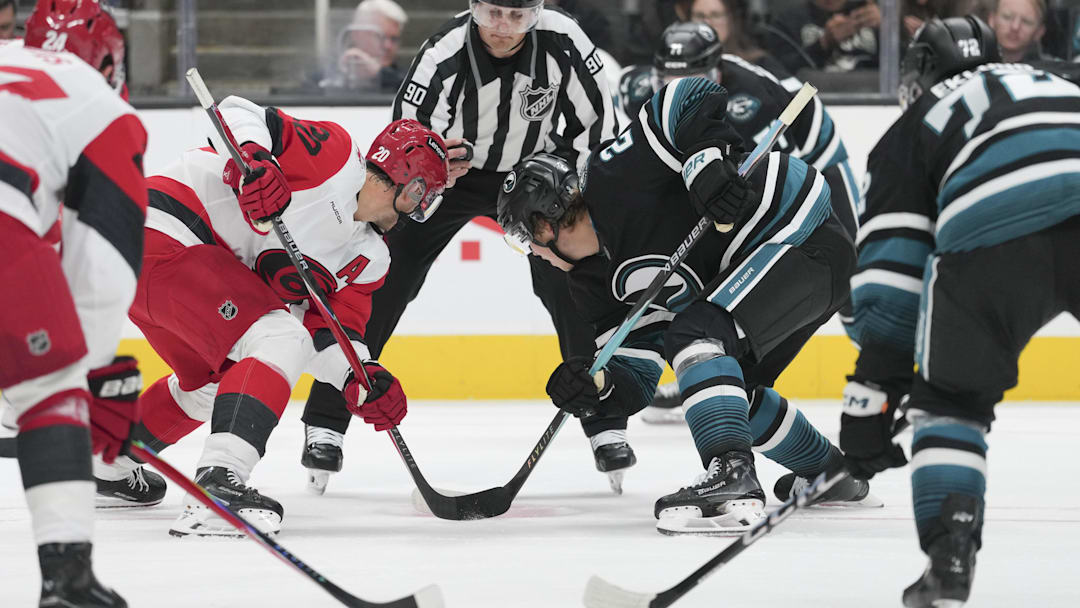 Oct 14, 2025; San Jose, California, USA;  Carolina Hurricanes center Sebastian Aho (20) and San Jose Sharks center Will Smith (2) face off during the third period at SAP Center at San Jose. Mandatory Credit: Stan Szeto-Imagn Images