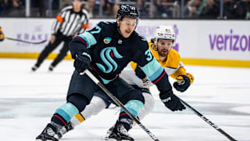 Nov 20, 2024; Seattle, Washington, USA;  Seattle Kraken forward Yanni Gourde (37) skates against Nashville Predators forward Tommy Novak (82) during the first period at Climate Pledge Arena. Mandatory Credit: Stephen Brashear-Imagn Images