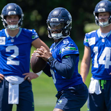 Seattle Seahawks QB Jalen Milroe looks to pass as Drew Lock and Sam Darnold watch at mini-camp.