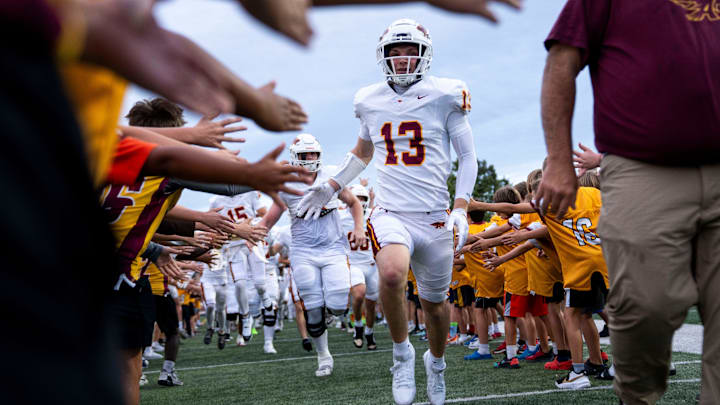 Ankeny’s Andrew Brandhorst (13) runs through a tunnel of Ankeny Junior Football players on Sept. 19, 2025, at Ankeny Stadium.