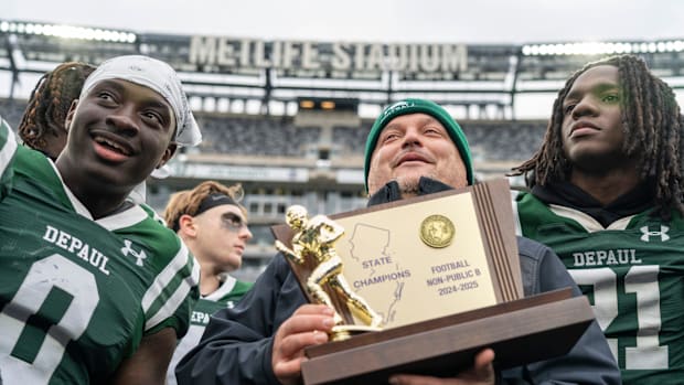 DePaul's head coach Nick Campanile holds the championship trophy with his team after a 33-21