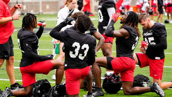 Cincinnati Bearcats players drink water together during football practice, Wednesday, July 31, 2024, at Nippert Stadium in Cincinnati.