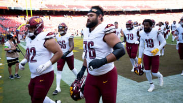 Washington Commanders offensive tackle Sam Cosmi (76) and others run into the locker room before the