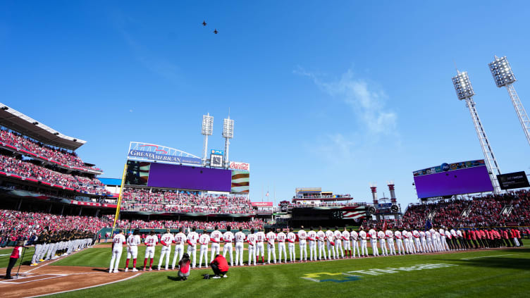 Players stand for the National Anthem as F-16s fly over the field for the 104th Cincinnati Reds Opening Day