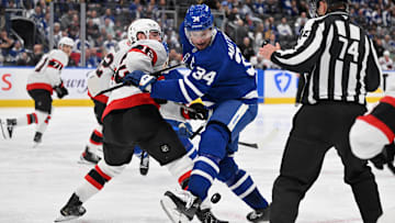 Apr 22, 2025; Toronto, Ontario, CAN;  Toronto Maple Leafs forward Auston Matthews (34) battles for the puck with Ottawa Senators forward Shane Pinto (12) in the third period in game two of the first round of the 2025 Stanley Cup Playoffs at Scotiabank Arena. Mandatory Credit: Dan Hamilton-Imagn Images