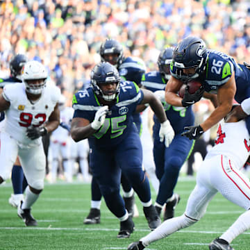 Nov 9, 2025; Seattle, Washington, USA; Seattle Seahawks running back Zach Charbonnet (26) leaps over Arizona Cardinals safety Jalen Thompson (34) for a touchdown during the second quarter at Lumen Field. Mandatory Credit: Steven Bisig-Imagn Images