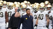 Nov 15, 2025; Pittsburgh, Pennsylvania, USA;  Notre Dame Fighting Irish head coach Marcus Freeman (middle) leads the team onto the field to play the Pittsburgh Panthers at Acrisure Stadium. Mandatory Credit: Charles LeClaire-Imagn Images