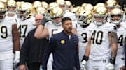Nov 15, 2025; Pittsburgh, Pennsylvania, USA;  Notre Dame Fighting Irish head coach Marcus Freeman (middle) leads the team onto the field to play the Pittsburgh Panthers at Acrisure Stadium. 