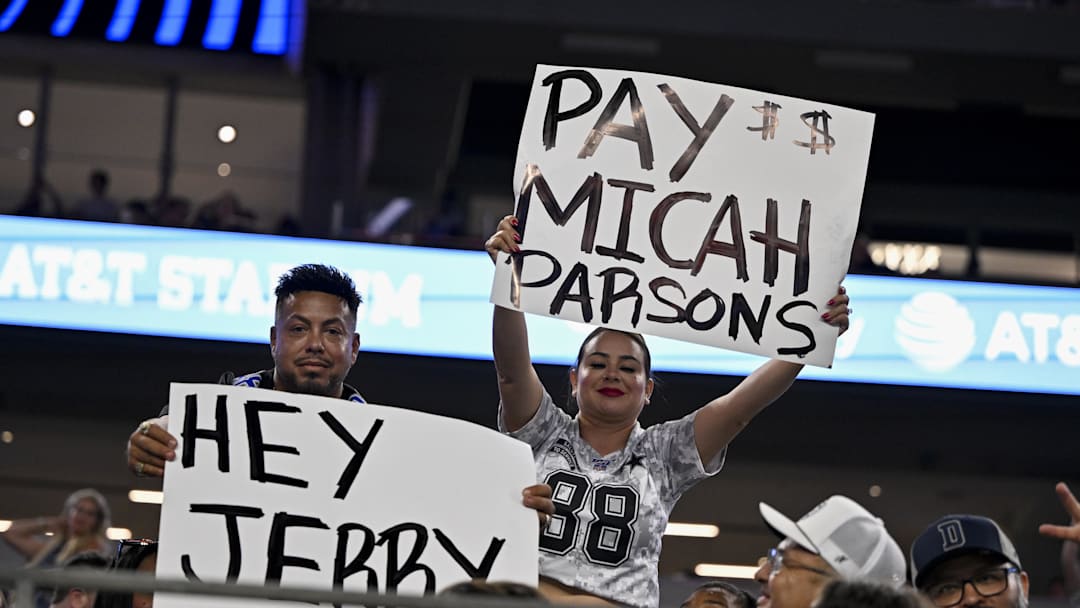 Aug 16, 2025; Arlington, Texas, USA; Dallas Cowboys fans hold up signs to owner Jerry Jones and defensive end Micah Parsons (11) during the second half of the game against the Baltimore Ravens at AT&T Stadium. Mandatory Credit: Jerome Miron-Imagn Images
