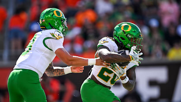 Oregon Ducks quarterback Dillon Gabriel (8) hands off the ball to Oregon Ducks running back Jordan James (20)